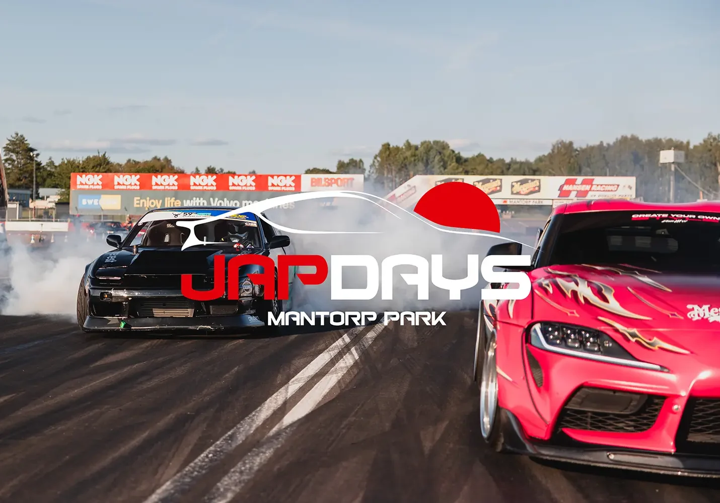Två bilar på en racerbana med däckrök, en svart och en rosa med lågor. Logotyper för "JapDays" och "Mantorp Park" överlagrar bilden. I bakgrunden finns reklambanderoller och en klar himmel.